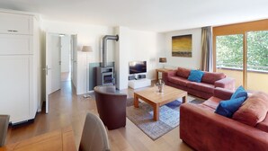 A modern living room with a sofa, coffee table, TV, and a fireplace. - Walensee House & Apartments, (Unterterzen), by Interhome (Unterterzen)