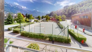 A sports court with a net, surrounded by greenery and buildings, with mountains in the background. - Walensee House & Apartments, (Unterterzen), by Interhome (Unterterzen)