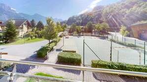Zona residencial con casas, una calle pavimentada y una cancha deportiva cercada.
