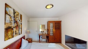 Una habitación de hotel con dos camas, un escritorio, un armario y un televisor.