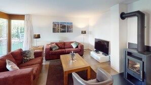 Una sala de estar moderna con sofá, mesa de centro, televisor, chimenea y obras de arte en la pared.