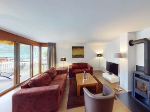 A modern living room with a sofa, a coffee table, a TV, and a fireplace. - Walensee House & Apartments, (Unterterzen), by Interhome (Unterterzen)