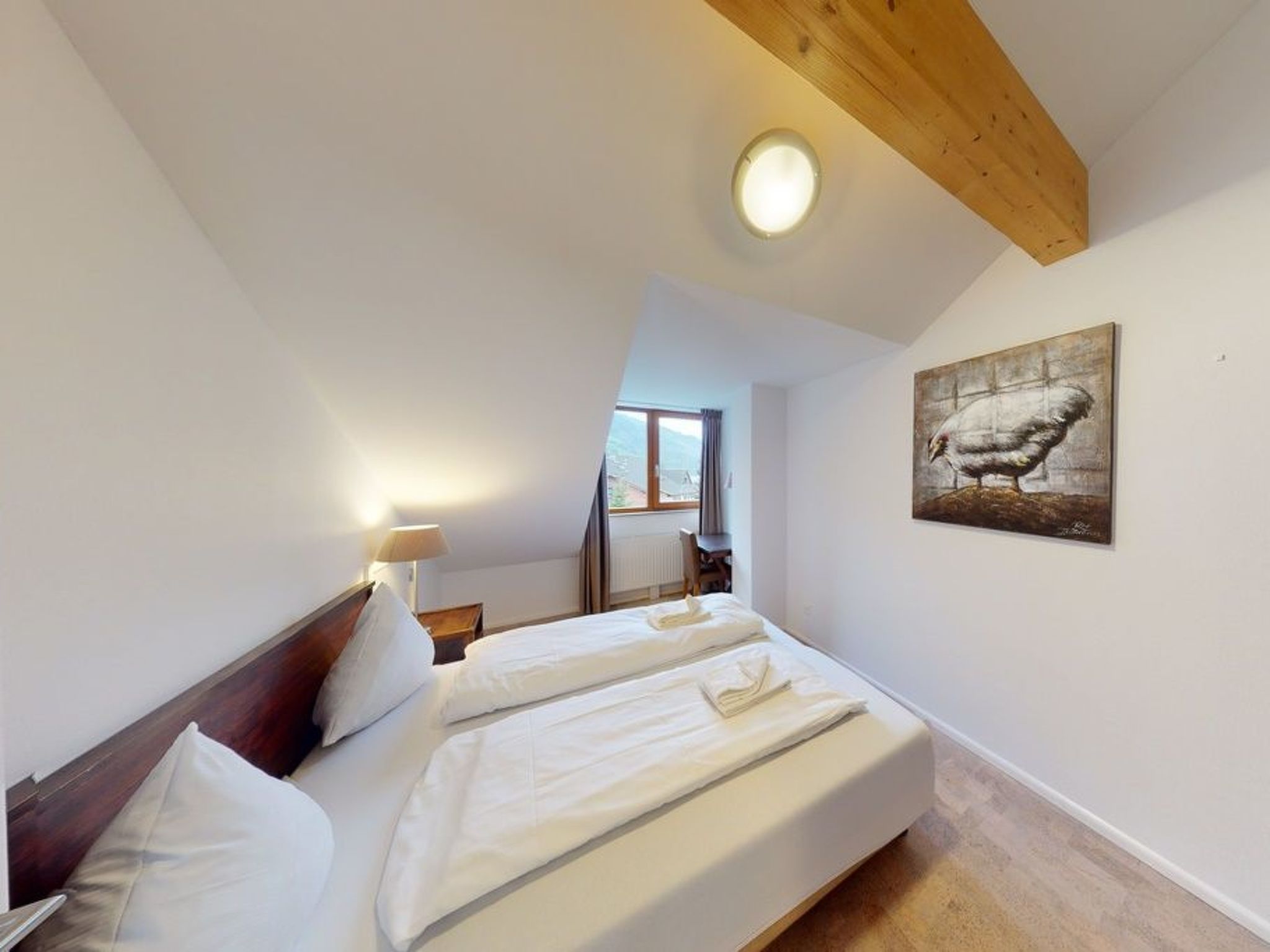 Une chambre à coucher avec un lit, une lampe, un tableau et une vue sur l’extérieur.