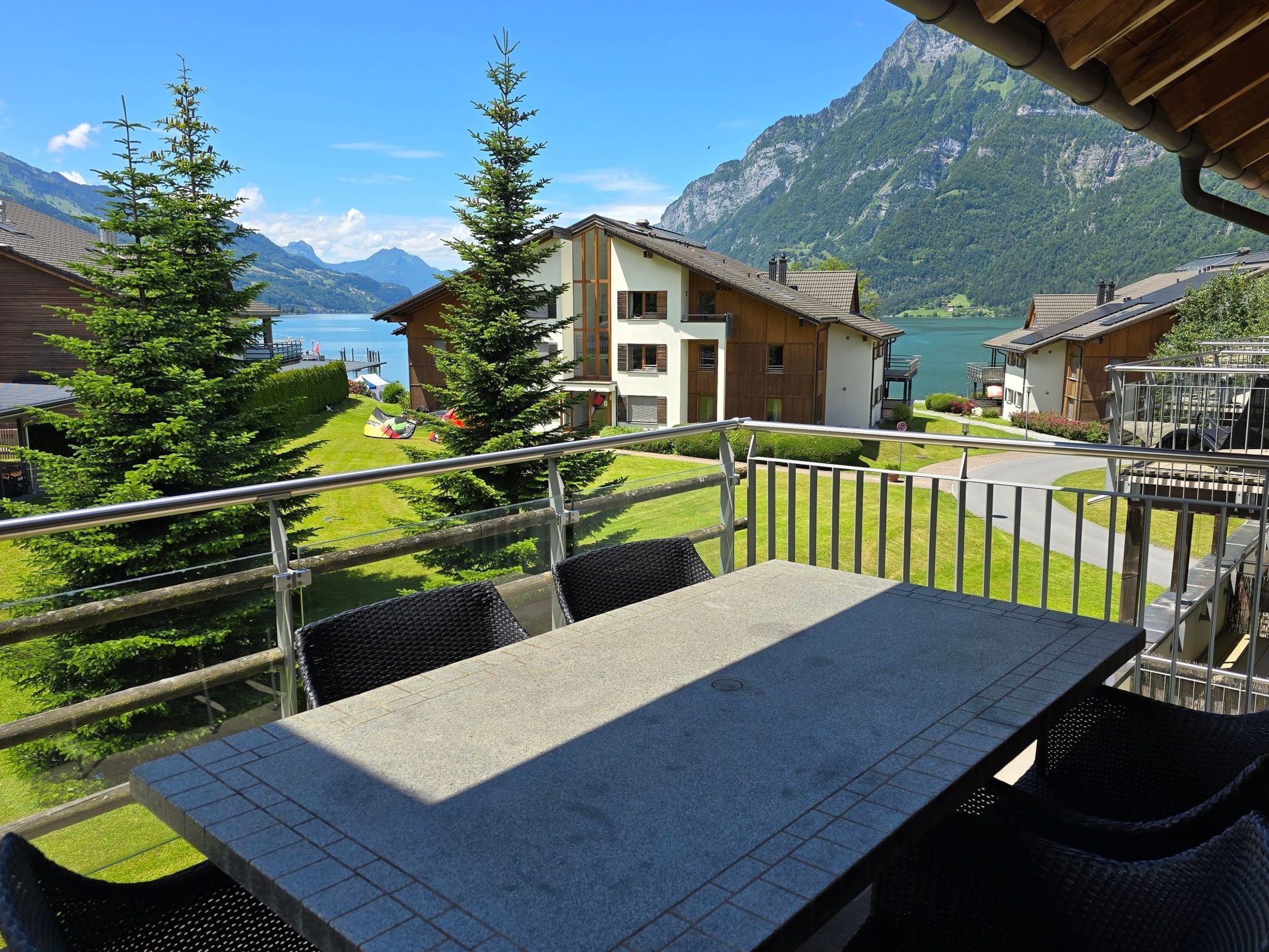 Un balcon avec une table et des chaises donnant sur un paysage montagneux avec un lac.