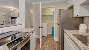 Una cocina moderna con gabinetes blancos, un refrigerador de acero inoxidable, horno integrado y encimera de granito.