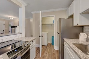 A modern kitchen with white cabinets, a stainless steel refrigerator, a built-in oven, and a granite countertop. - 2-bedroom apartment in tranquil Durham with cool AC breeze (Durham)
