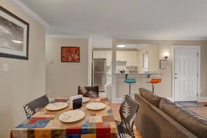 A dining area with a table set for four, a sofa, and a kitchen in the background. - 2-bedroom apartment in tranquil Durham with cool AC breeze (Durham)