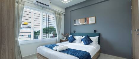 Un dormitorio con cama, cortinas, aire acondicionado, ventilador de techo y ventana con vistas.