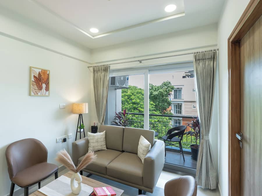 Una sala de estar moderna con un sofá, sillas, una mesa y un ventanal con cortinas.