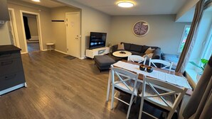 A living room with a sofa, TV, and a dining area with chairs and a table. - Notodden Sentrum Apartment NO 14 (Telemark)