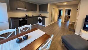 A modern kitchen with built-in appliances, a dining area with a table and chairs, and a living space with a sofa and TV. - Notodden Sentrum Apartment NO 14 (Telemark)