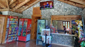 Un interior rústic amb paret de pedra, bigues de fusta, una parada de mossegar i un paviment de rajola.