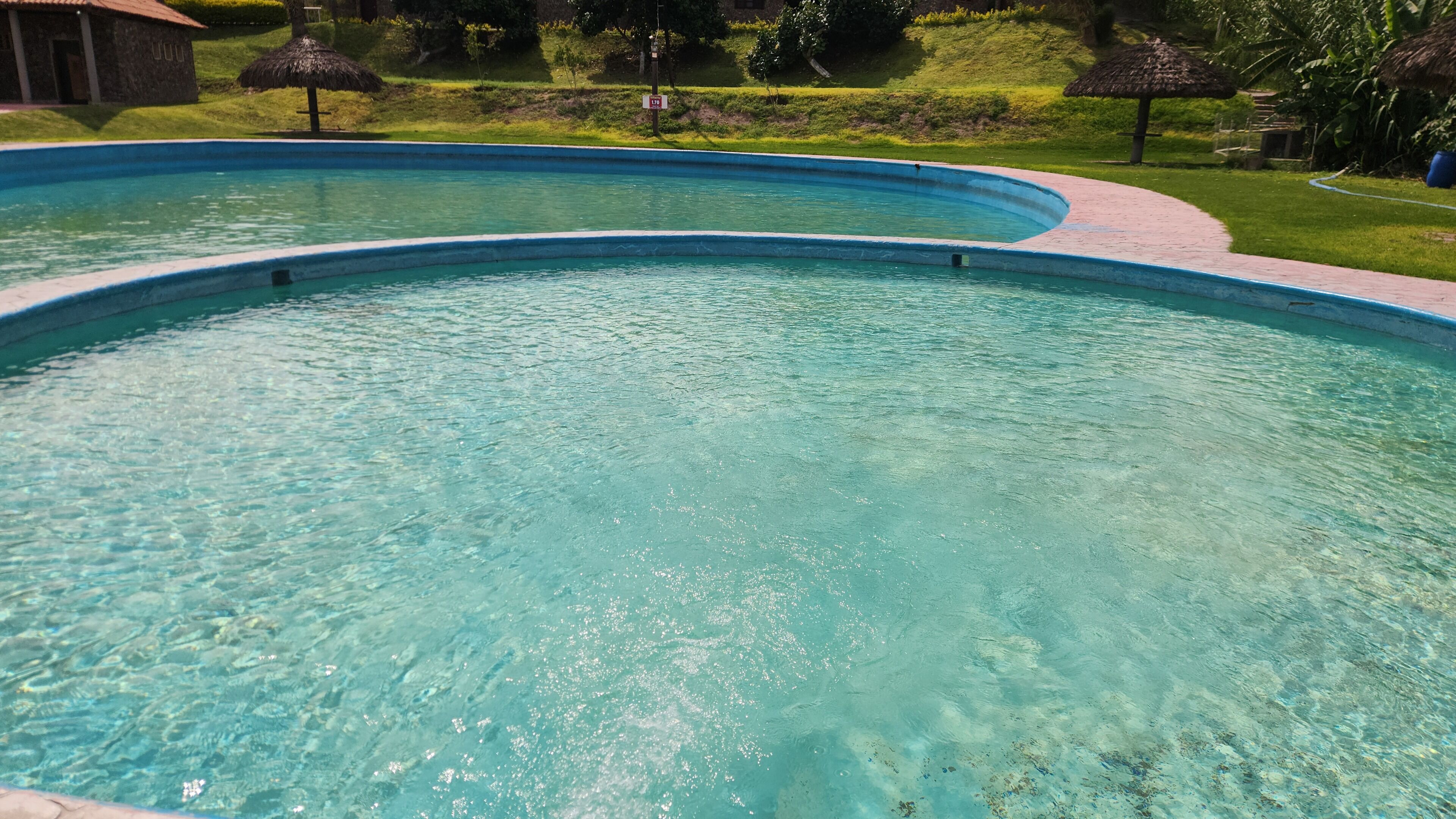 Ein klares Schwimmbecken mit einer gepflasterten Laufbahn darum.