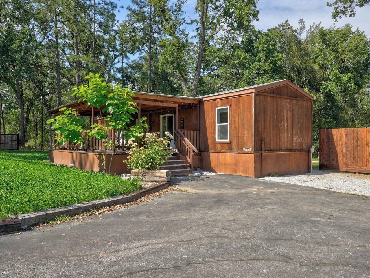 A wooden cabin with a porch, steps, and a small garden.