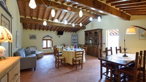 Un vaste espace dédié à la salle à manger, avec un haut plafond en bois, une table à manger entourée de chaises et un buffet en arrière-plan.