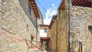 Une étroite ruelle pavée, avec un escalier en bois menant à un bâtiment dont le toit est recouvert de tuiles.