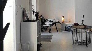 A room with a bed, a desk, a chair, a small table with a lamp, a radiator, and a wall-mounted picture. - The Courtyard by the Seaside (Calasetta)