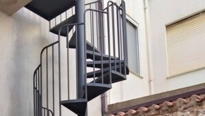 A spiral staircase with metal railings, leading to an upper floor. - The Courtyard by the Seaside (Calasetta)