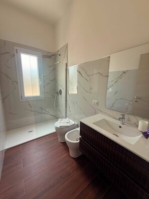 A modern bathroom with a glass-enclosed shower, a toilet, a bidet, and a vanity with a sink. - Casa Volqart (Località Rogana I)