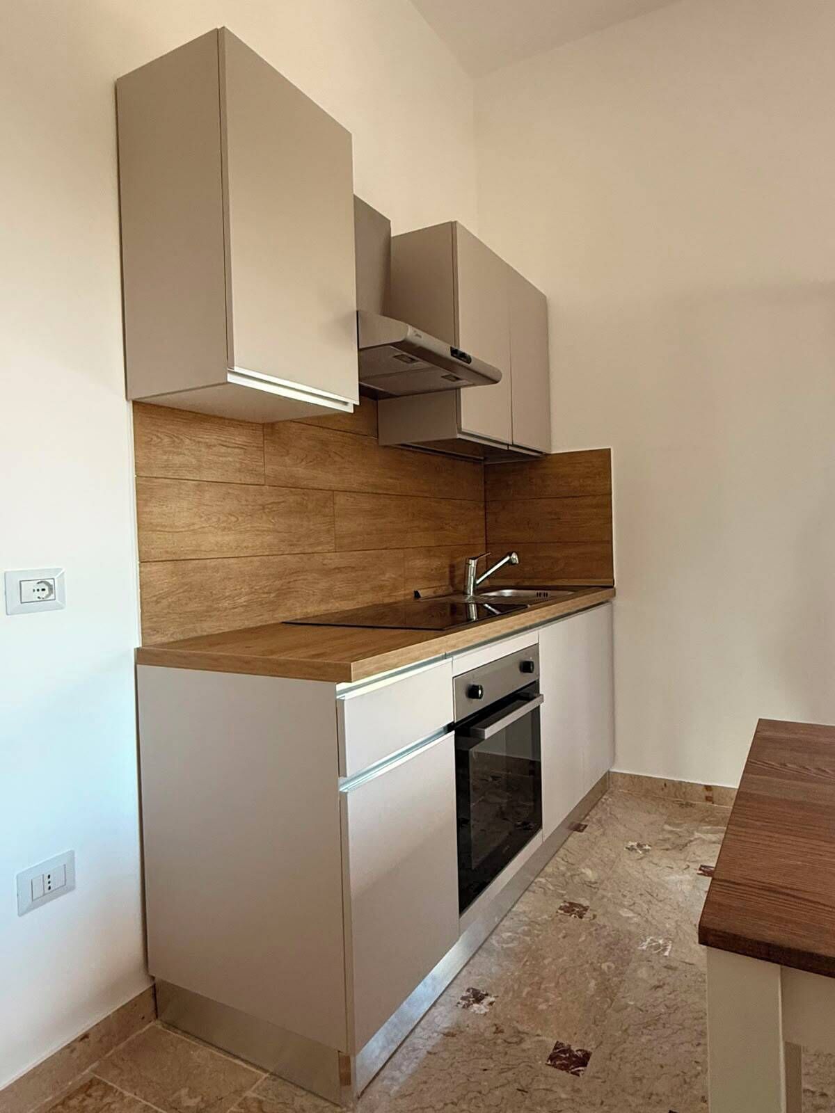 Uma cozinha compacta com forno embutido, pia e bancada de madeira.