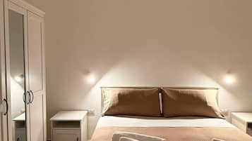 Um quarto com uma cama, mesa de cabeceira, guarda-roupa e espelho.
