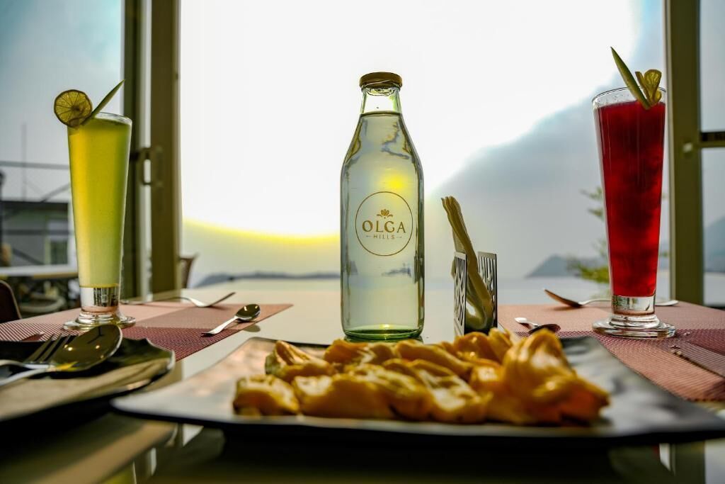Une table avec une bouteille d’Olga Hills, deux verres et une assiette de nourriture.