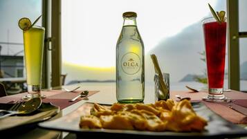 Une table avec une bouteille d’Olga Hills, deux verres et une assiette de nourriture.