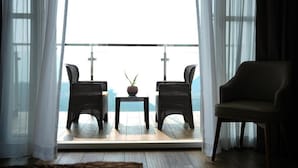 A balcony with wicker chairs, a small table, and a potted plant.