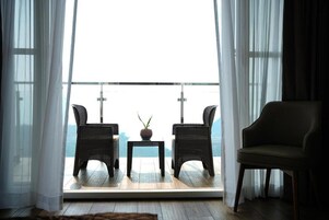 A balcony with wicker chairs, a small table, and a potted plant.
