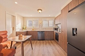 Eine moderne Küche mit Holzausstattung, einem Edelstahlkühlschrank und einem Geschirrspüler.