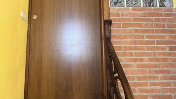 Une porte en bois avec une poignée de porte en laiton, un mur en briques et une fenêtre avec des vitraux colorés.
