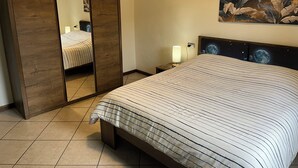 A bedroom with a bed, a nightstand, a lamp, a painting, and a wardrobe. - La Casita del Lago is ideal for families or groups. Thank you for choosing us (Lombardia)