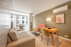 Ein modernes Wohnzimmer mit einer Couch, einem Esstisch mit Stühlen, einem Fernseher und einer Lampe.