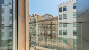 Een modern gebouw met een glazen balkon met uitzicht op oudere gebouwen.