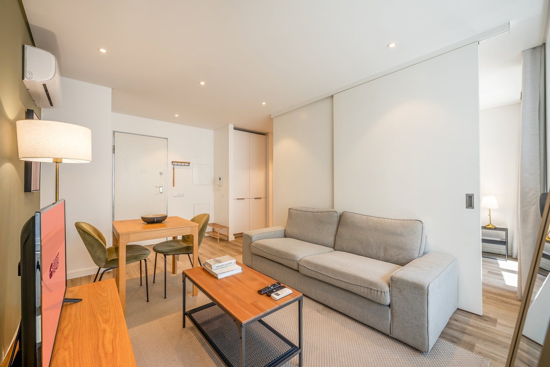 A modern, well-lit room with a sofa, a dining table, and chairs.