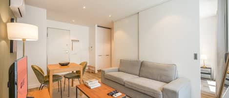 A modern, well-lit room with a sofa, a dining table, and chairs.