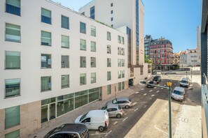 Un immeuble à plusieurs étages, doté d’une architecture moderne, avec de grandes fenêtres et un espace de stationnement où sont garées plusieurs voitures.
