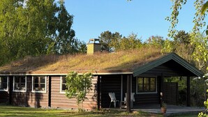 A rustic cabin with a covered porch, a small garden, and a hilltop setting. - Charming log cabin in Tisvilde (Tisvilde)