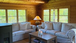 A cozy cabin interior with a wooden ceiling, two sofas, a coffee table, and a lamp. - Charming log cabin in Tisvilde (Tisvilde)