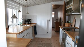 Eine Küche mit Holzarbeitsplatten, einem eingebauten Backofen, einer Kaffeemaschine und einer Pendelleuchte.