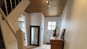 Eine Holztreppe führt zu einer Zwischenebene mit einem Spiegel, einem Holzschrank und einer Tür mit Fenster.