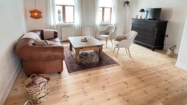 Ein Wohnzimmer mit Sofa, Couchtisch, Sesseln, Fernseher und Kamin.