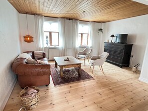 Un salon comprenant un canapé, une table basse, des fauteuils, un téléviseur et une cheminée.