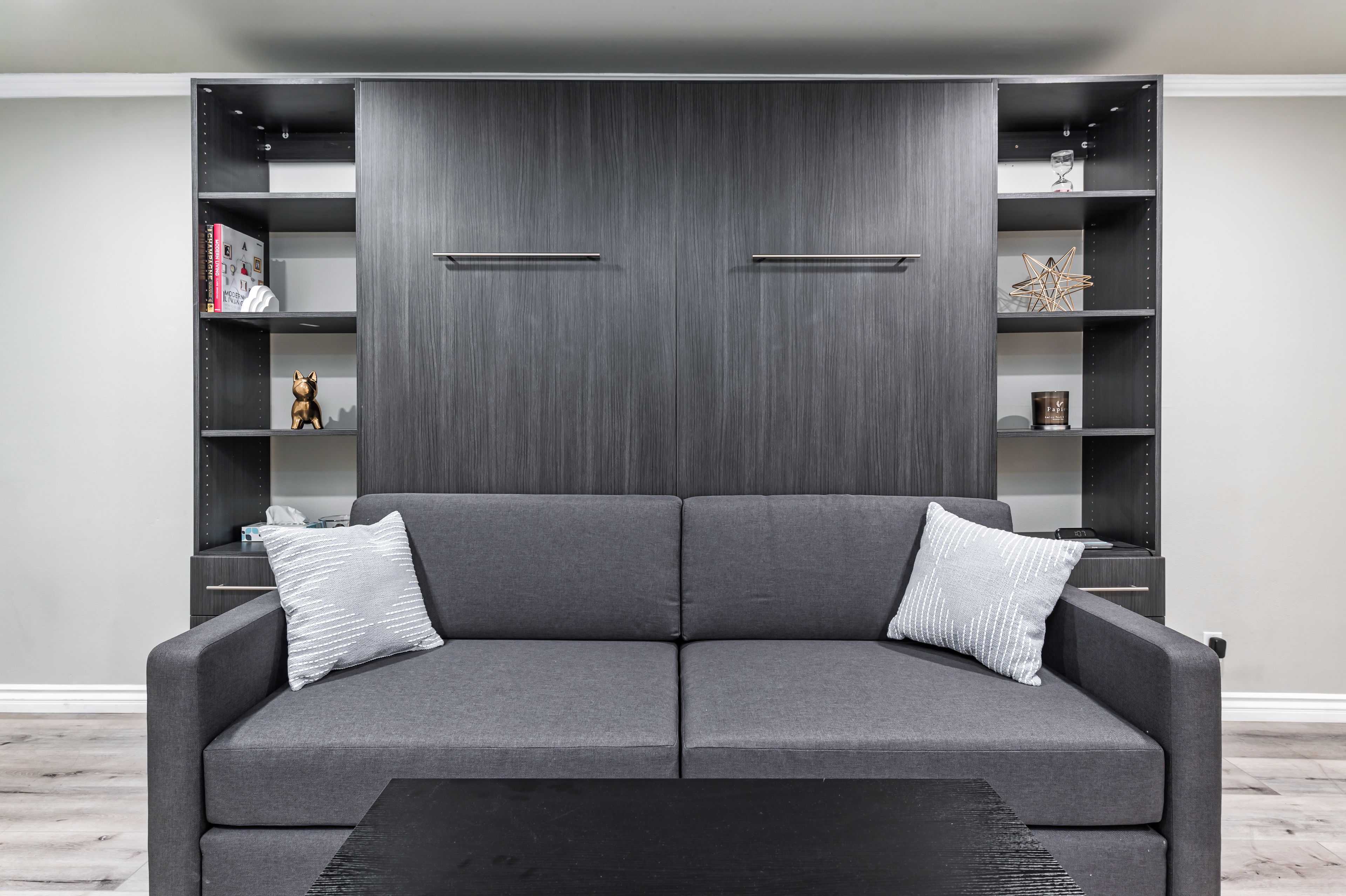 Ein modernes Wohnzimmer mit einem grauen Sofa, zwei Beistelltischen und einem schwarzen Couchtisch.