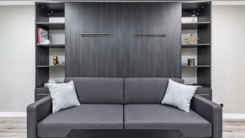 A modern living room with a grey sofa, two side tables, and a black coffee table.