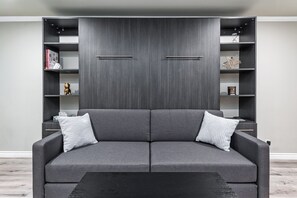 Ein modernes Wohnzimmer mit einem grauen Sofa, zwei Beistelltischen und einem schwarzen Couchtisch.
