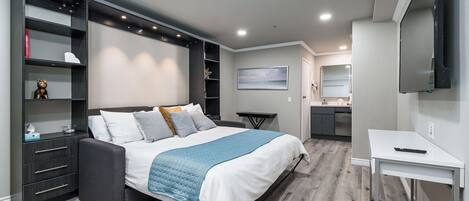 Une chambre moderne comprenant un lit, des étagères intégrées, un bureau et un téléviseur.
