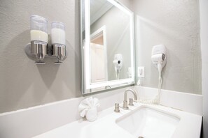 A bathroom with a sink, hand cream and soap dispensers, a hair dryer, and a towel. - SGV+Disney+Rose Bowl • Quadruple Rm near DTLA (Alhambra)