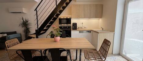 A modern kitchen with a dining area, a staircase, and a large window.