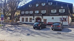 A traditional building with a sloped roof, multiple windows, and a sign indicating a restaurant. Two cars are parked in front. - Markterwirt (Altenmarkt im Pongau)